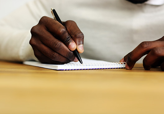 man sitting behind desk signing document