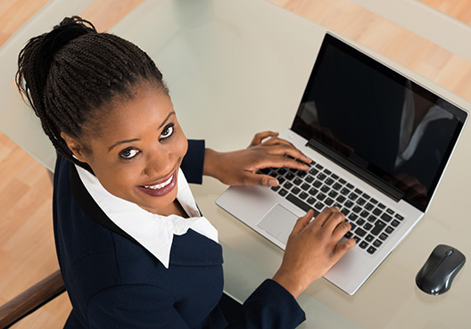 Lady typing on her laptop looking at the camera