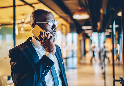 man standing in office foyer talking on a cellphone