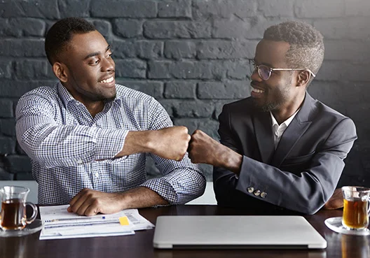Two working professionals enjoying tea and fist bumping